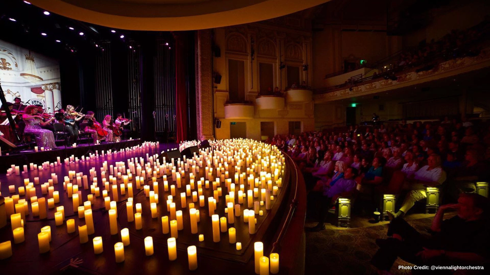 Vienna Light Orchestra playing on stage surrounded by candle light and audience